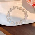 Detaillierte Nahaufnahme eines Armbands aus klarem und hellblauem Glas auf weißer Seide - Frischer einfacher Glasperlenstil (45#) / Weiß-Blau