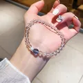 Nahaufnahme eines eleganten Armbands aus klaren Kristallperlen mit Perle und blauem Akzent. - Minimalistischer High-End-Perlenstil (46#) / Weiß-Blau