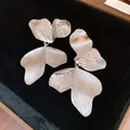 Detailed macro view showing the intricate leaf texture of silver pendant earrings on black velvet - Silver
