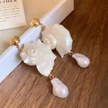 Close-up detail of elegant shell and baroque pearl drop earrings on a jewelry box - White