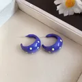 Detail view showing blue enamel C-shaped stud earrings with charming yellow polka dots - Purple