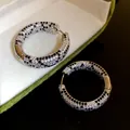 Dettaglio di orecchini a cerchio placcati oro 18K con zirconi bianchi e neri - Argento (Placcato Oro Vero)