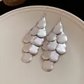 Detailed view of silver matte layered teardrop tassel earrings on a textured plate - Matte Teardrop Tassel / Silver