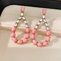 Dettaglio ravvicinato di orecchini a goccia con pietre rosa e strass scintillanti - Rosa