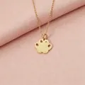 Close-up of a gold stainless steel paw print pendant necklace with a small diamond accent. - Gold
