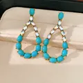 Vista dettagliata di eleganti orecchini a goccia con turchese e strass in astuccio. - Blu