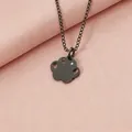 Macro view of a black stainless steel paw print necklace with a sparkling rhinestone detail. - Black