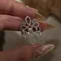 Detail of vintage hollow flower ring with pavé zircons held by fingers - Silver