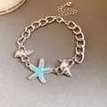 Close-up of silver-tone starfish and shell charm chain bracelet with blue studs. - Silver-Blue