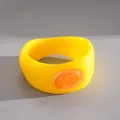Detailed macro view of a chunky yellow resin bangle featuring a swirl orange oval accent - Yellow