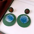 Close-up detail of vintage resin earrings featuring a blue rose on a green circular base. - Silver Needle-Green-Blue
