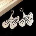 Close-up detail of matte silver ginkgo leaf drop earrings displayed on black velvet background - Silver