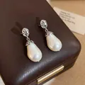 Close-up detail of elegant water drop pearl earrings with pleated silver metal accents on box - Wrinkled Oval Pearl / Silver