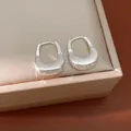 Primo piano di orecchini a cerchio a forma di U testurizzati con finitura argento. - Fibbia per orecchie / Argento