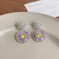 Elegant daisy drop earrings featuring purple cubic zirconia petals and yellow centers. - Pink
