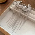 Detailed view of silver-toned C-shaped earrings with long bead-chain tassels in a tray - Silver