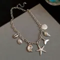 Close-up of silver marine charm necklace with starfish and seashell pendants - Necklace / Silver