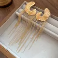 Elegant gold C-shaped tassel earrings featuring long ball chain drops in a jewelry box display - Gold