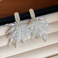 Macro view of elegant rhinestone and white pearl tassel earrings on a soft velvet display - Tassel Studs / White