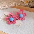 Close-up of pink resin flower stud earrings with blue center on a fabric background - Silver Earring Post Style / Pink-Blue