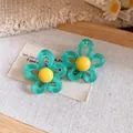 Detail showing teal resin flower earrings with yellow centers on rustic fabric background - Silver Earring Post Style / Green-Yellow