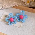 Close-up view of blue resin flower stud earrings with pink center on canvas - Silver Earring Post Style / Blue-Pink