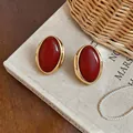 Close-up of vintage oval resin earrings featuring a gold-toned frame and deep red center - Oval Studs / Red
