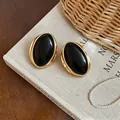 Vintage oval resin stud earrings with gold-tone frame on a classic book backdrop - Oval Studs / Black