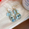 Detailed macro view of handmade resin teardrop earrings with real blue dried flowers - Lake Blue