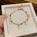 Primo piano di un bracciale in acciaio inossidabile dorato con perline colorate e ciondoli a stella - Bracciale / Oro-Multicolore