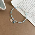 Gedetailleerde weergave van een lichtblauwe kralenarmband met zeester en kristal - Armband-Blauw