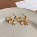 Macro view of gold C-shaped hoop earrings with zircon heart and star charms - C-Shaped Heart Star / Gold