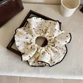 Dettaglio di uno scrunchie in seta crema a pois neri con elegante bordo in pizzo bianco - Elastico per capelli / 1 Pezzo / Bianco
