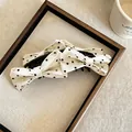 Primo piano di eleganti fermagli per capelli con fiocco in tessuto a pois in una cornice - Clip a Torsione / 1 Pezzo / Bianco