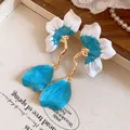 Macro detail view of elegant blue and white enamel flower earrings with golden stems - Petal Style / Blue