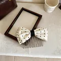 Dettaglio di un pettine per capelli con fiocco in tessuto a pois bianchi su sfondo. - Bastoncino per capelli / 1 Pezzo / Bianco
