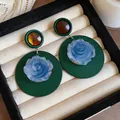 Detailed macro shot of vintage French style dark green rose earrings in a jewelry box - French Vintage Round Rose / Dark Green-Blue