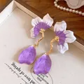 Detailed close-up view of elegant purple enamel flower earrings on a display tray - Petal Style / Purple