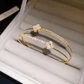Macro detail of gold-plated bangle with zircon-studded and mother-of-pearl clover motifs - Gold