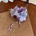 Exquisite detail of a purple fabric lily hair clip with pearl tassels and elegant ribbons. - Single Duckbill Clip Style / Purple