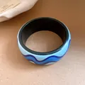Gros plan détaillé d'un bracelet en résine avec motif de vagues bleues et intérieur noir - Noir-Bleu