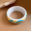 Gros plan d'un bracelet jonc rétro en résine avec des motifs de vagues bleues et orange - Blanc-Jaune