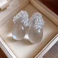 Dettaglio dei moderni orecchini a goccia in resina con decorazioni di piccole perle bianche fini - Goccia / Bianco