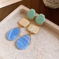 Close-up view of vintage resin drop earrings with blue, cream, and green geometric charms. - Blue