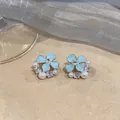 Detailed close-up of light blue enamel flower stud earrings with pearls and zircons - Flower Style (HE33476) / Blue