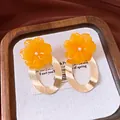 Close-up detail of stylish orange resin flower earrings with large golden oval hoops - Flower Oval Style (HE34017) / Silver Earring Post - Gold - Yellow