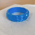 Detailopname van een blauwe doorschijnende hars armband met een gehamerde textuur. - Blauw