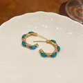 Detailed view of vintage C-shape earrings with turquoise stones and clear zircons. - C-Shaped Luxury Vintage Style / Gold-Blue