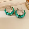 Detailed macro view of silver-tone hoop earrings featuring emerald green baguette crystals - Green