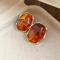 Detalle de pendientes ovalados de resina ámbar con bordes dorados de estilo vintage - Ámbar